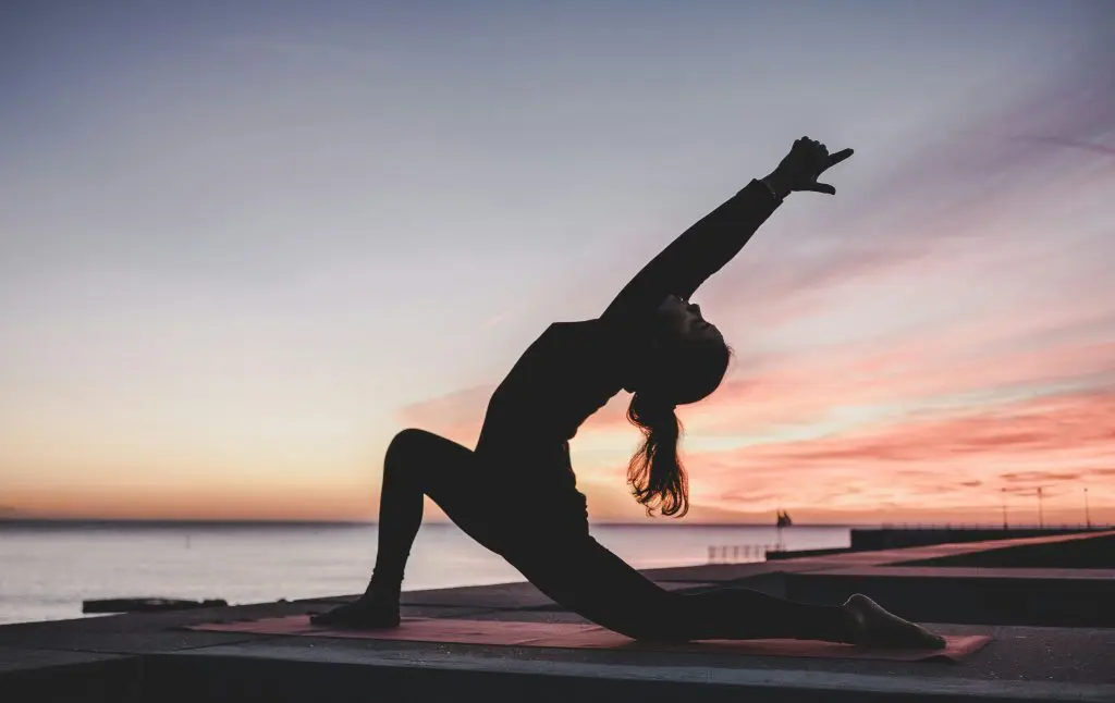 silhueta de uma mulher praticando yoga em na praia